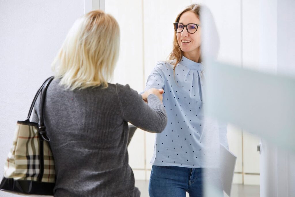 Mitarbeiterin aus der Hausverwaltung die eine Kundin freundlich im Büro empfängt.